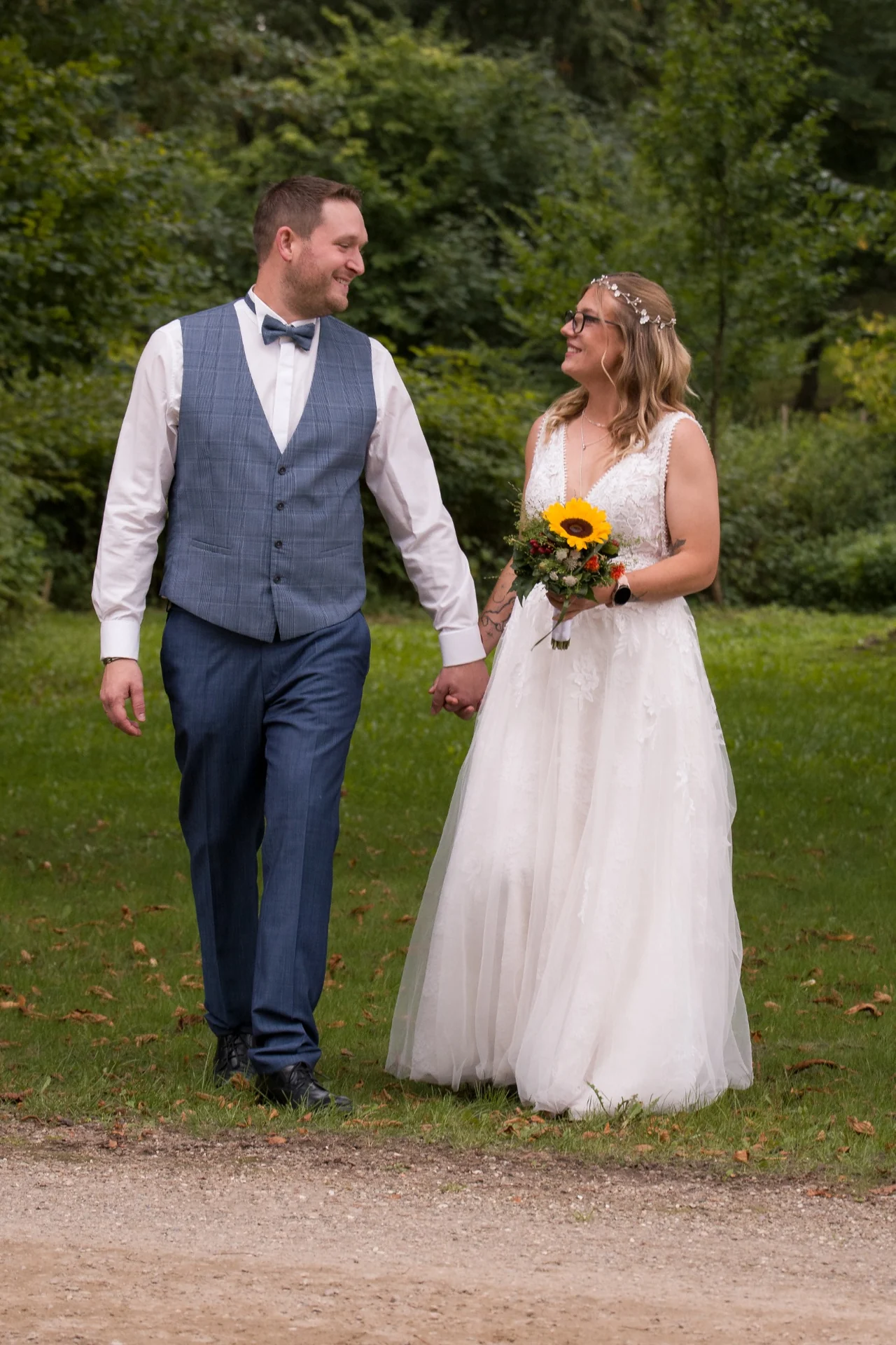 Das Hochzeitspaar geht Hand in Hand über die Wiese und schaut sich an.