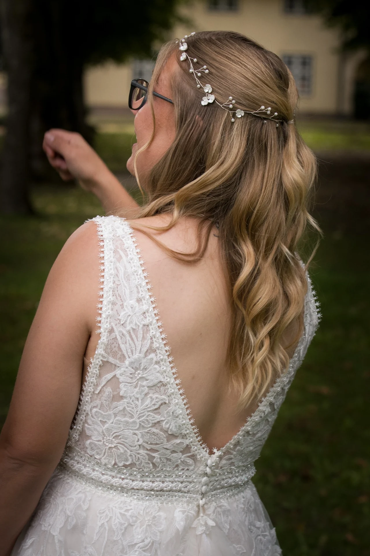 Die Braut von hinten: das Spitzenkleid und feiner Haarschmuck im lockeren Haar.